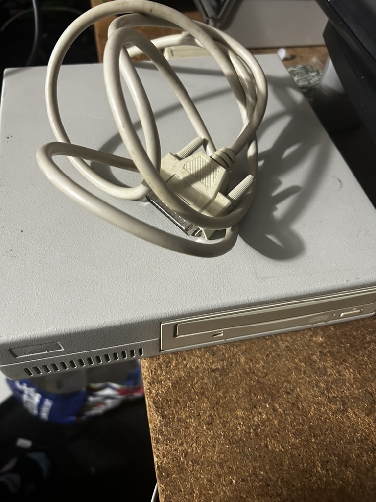 Vintage Apple external hard drive side view with an old SCSI cable coiled on top
