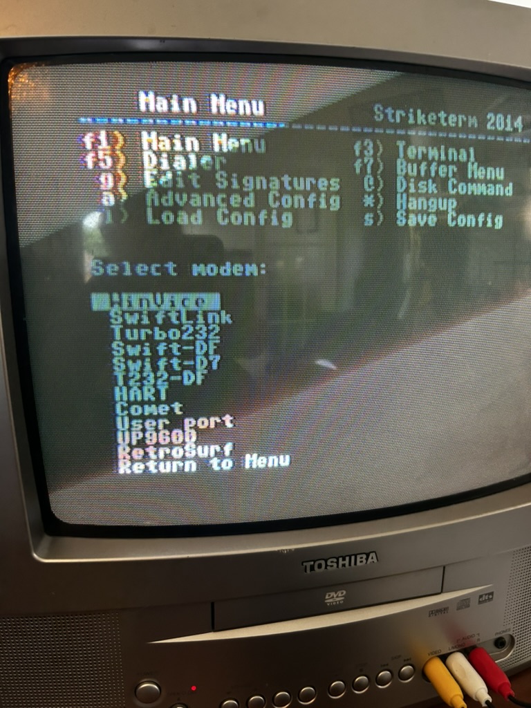 Toshiba CRT television displaying the Striketerm 2014 terminal program running on a Commodore 64, with modem selection menu visible