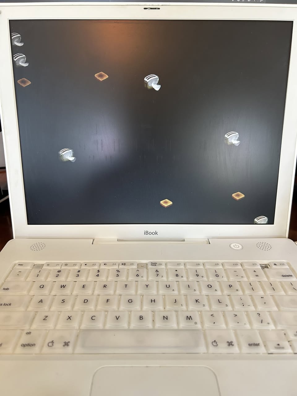 Apple iBook laptop with a classic screensaver running on its display