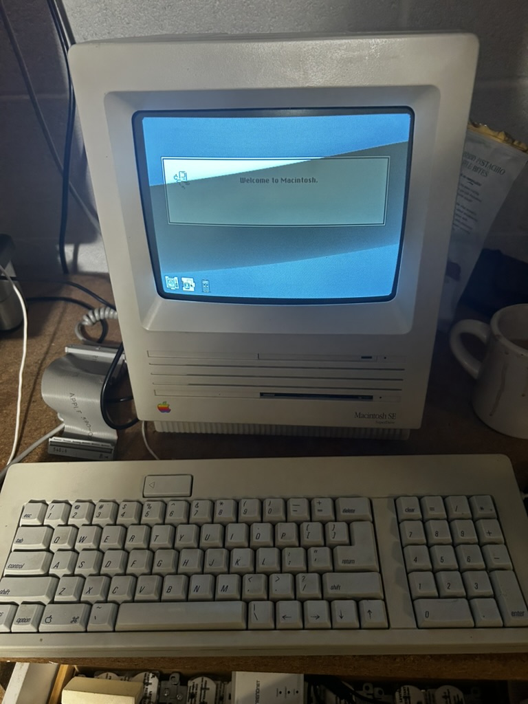 Macintosh SE all-in-one computer displaying the Welcome to Macintosh startup screen