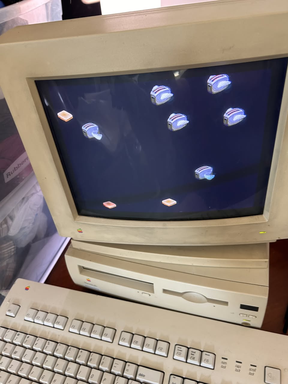 Vintage Macintosh desktop and CRT monitor with rainbow Apple logo displaying a colorful screensaver