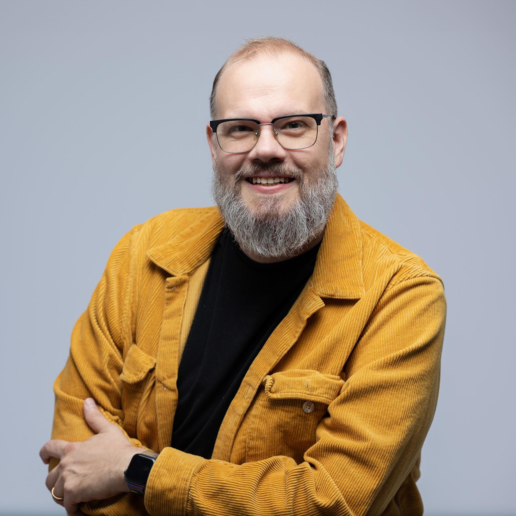 A photo of Eric Near, wearing a yellow corduroy jacket and a black t-shirt.